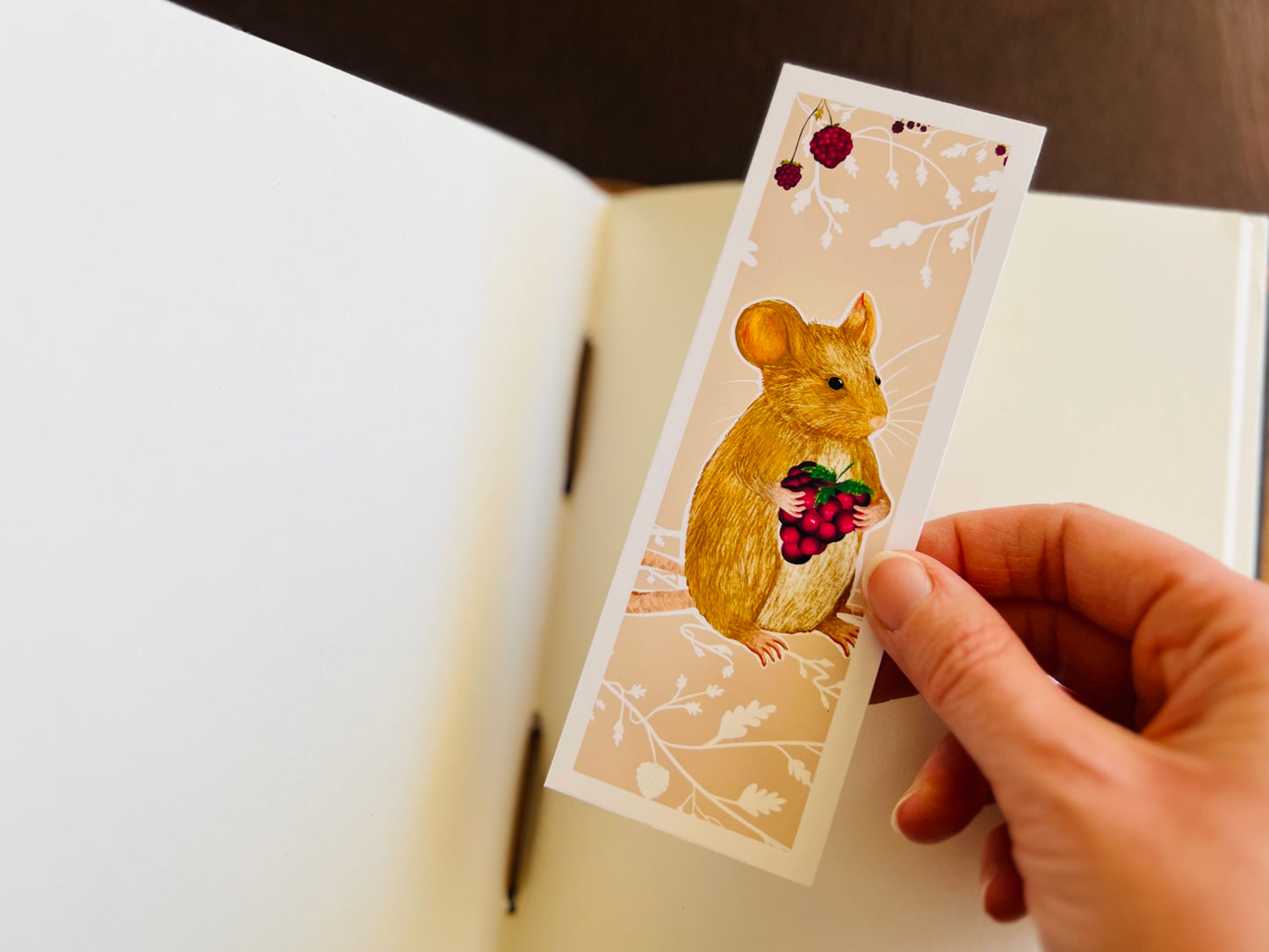 Mouse bookmark being placed into an open sketchbook.