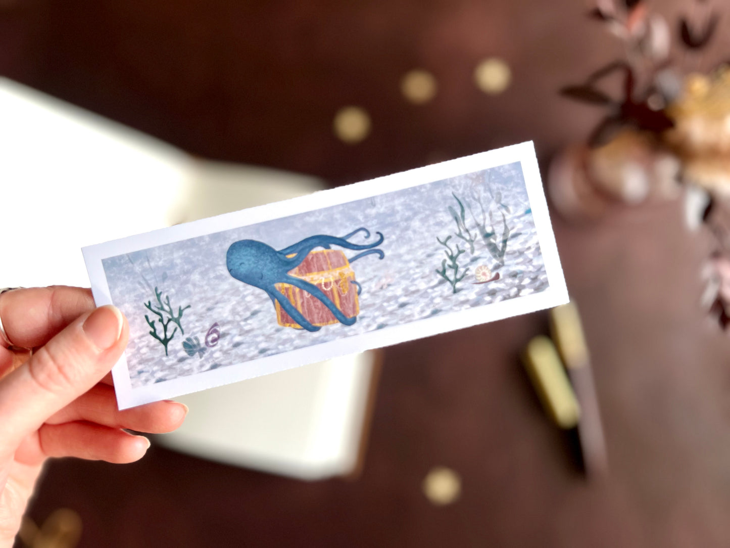 Nautical bookmark with blue ocean background and blue octopus illustration. White border. Handcrafted bookmark.