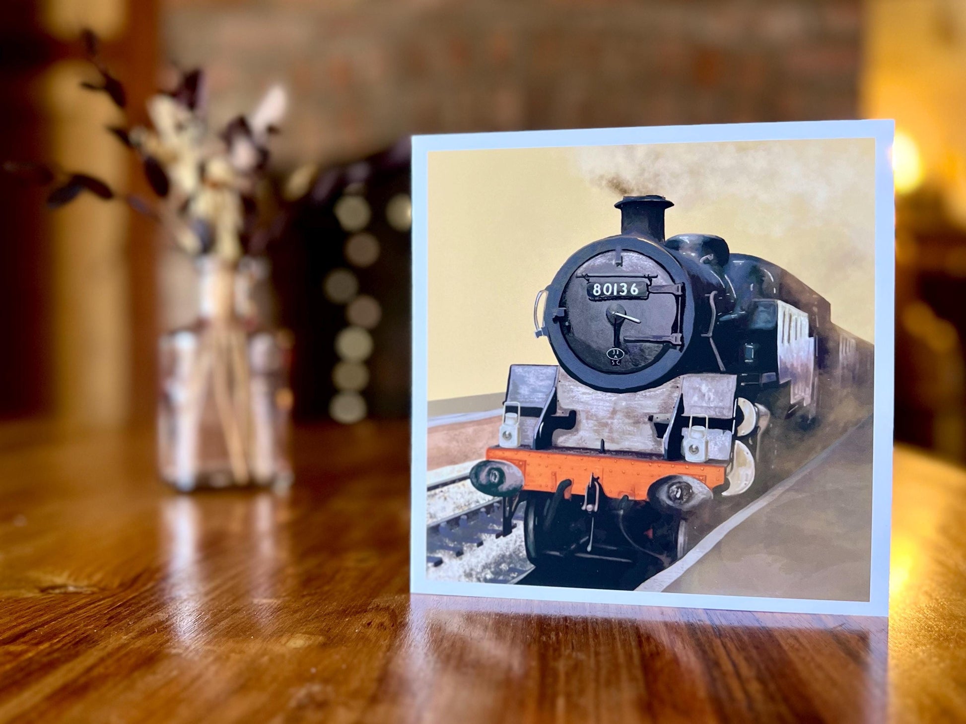 Artisan illustrated greeting card featuring steam engine 80136 from the North Yorkshire Moors Railway on a yellow background, displayed standing upright on a tabletop. Heritage railway art card design suitable for train enthusiasts and steam locomotive lovers.