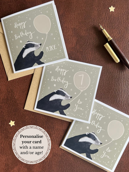 Three personalised badger birthday cards with custom names and milestone ages displayed with Kraft envelopes on rustic tabletop, showing custom birthday cards for any age