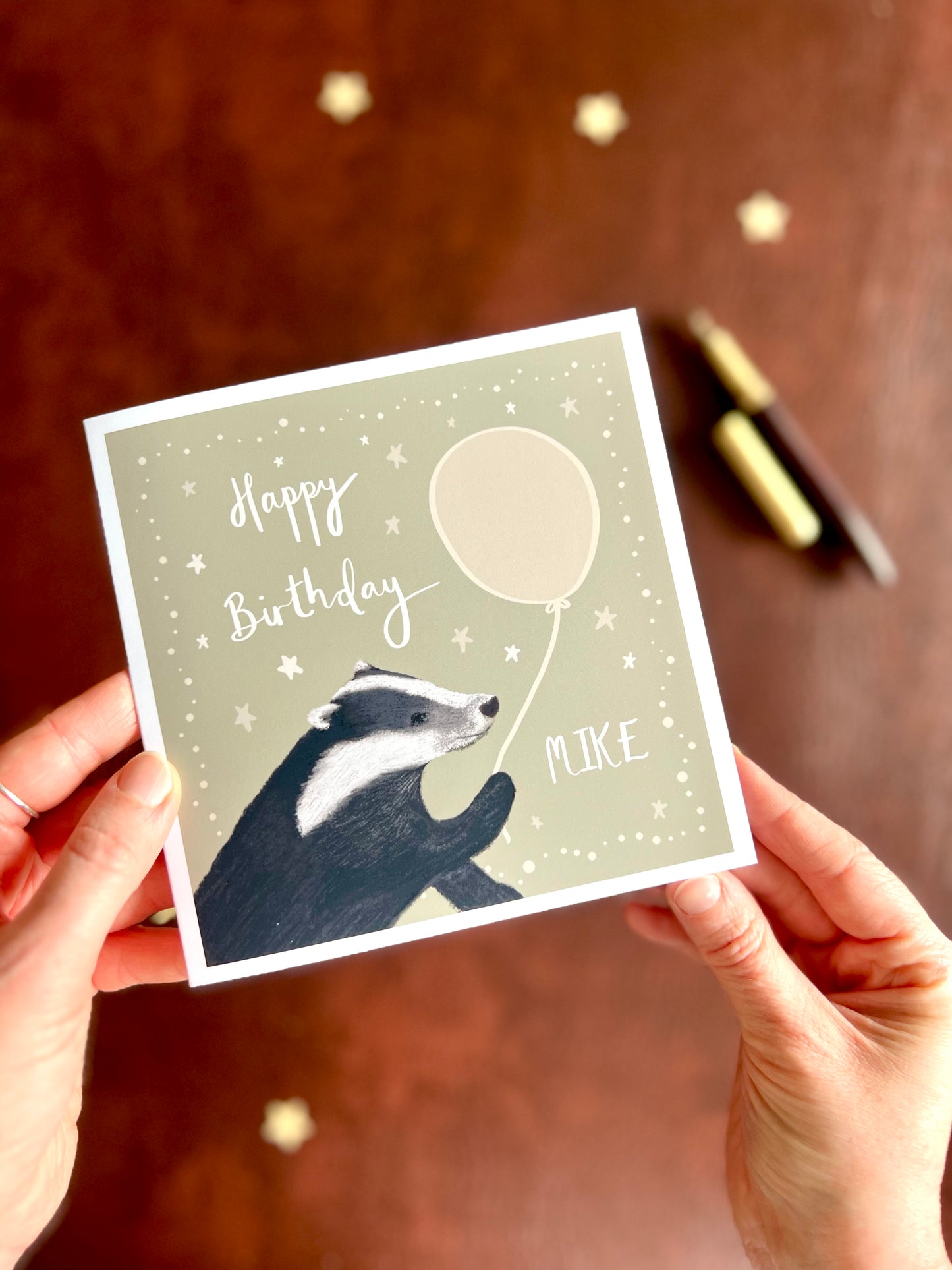 Personalised birthday card with custom name and illustrated woodland design held in hands with fountain pen in background, handmade artisan greeting card with free personalisation and quick turnaround in Yorkshire studio