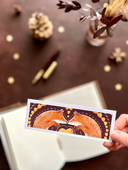 Bookmark featuring two woodland foxes. Special bookmark for reading gift or wellbeing gift to treat yourself. Maroon background with picture book style illustration of foxes. 