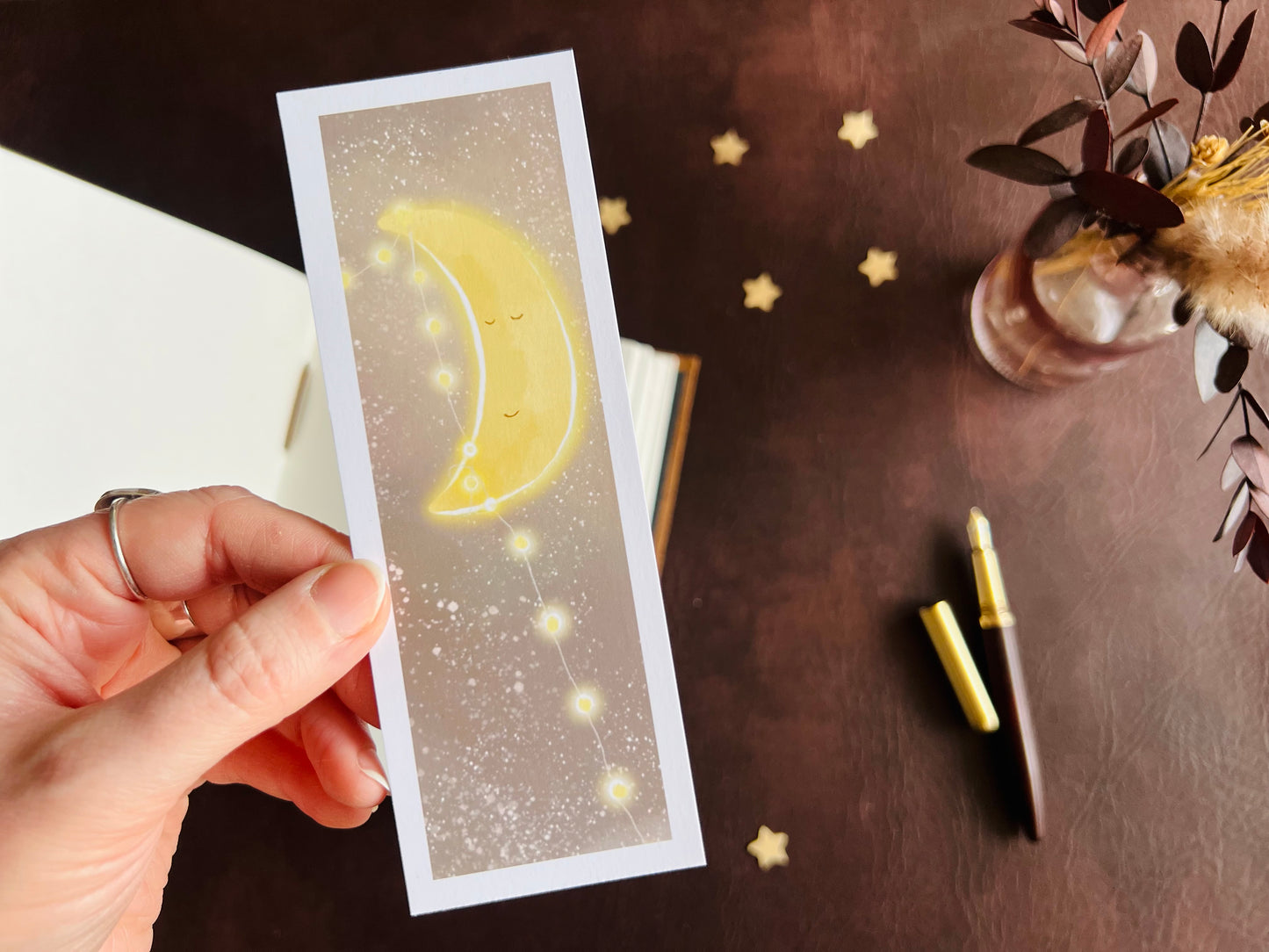Adorable sleeping moon illustration on a bookmark / page marker which has been handcrafted by the artist Hayley Victoria. Nighttime design with moon, stars and fairy lights. 
