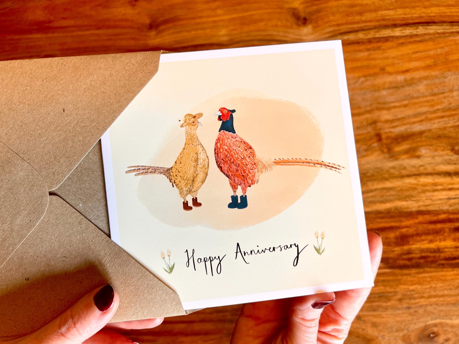 Handcrafted anniversary greeting card with a lemon yellow background featuring an illustrated male and female pheasant in a countryside wildlife theme. Premium illustrated card design supplied with a recycled 110gsm kraft envelope.
