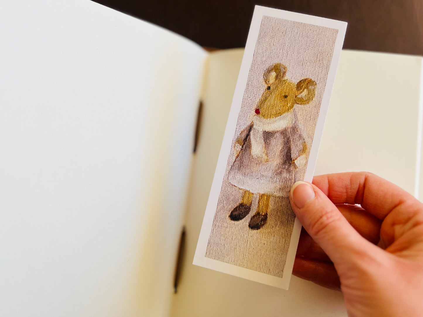 Mouse bookmark being placed into an open sketchbook.