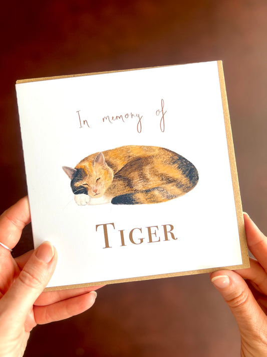 Personalised calico cat memorial card featuring a peaceful sleeping ginger, black and white tortoiseshell cat illustration with “In memory of” text above and the cat’s name below the artwork.