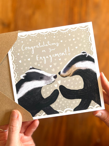 Close-up of a high-quality handmade engagement card featuring the text “Congratulations on Your Engagement” with a picture-book style badger illustration on a soft sage green background, showcasing a unique and thoughtful design, premium quality finish, rustic woodland aesthetic, and a gender-neutral engagement card suitable for Mr & Mr, Mrs & Mrs or Mr & Mrs couples, also ideal as a meaningful gift for son and daughter in law or daughter and son i