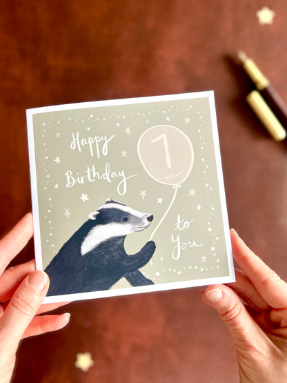 Hands holding personalised woodland birthday card with custom age balloon and illustrated badger design, handmade greeting card with rustic aesthetic, ideal for milestone celebrations and unique birthday gifts