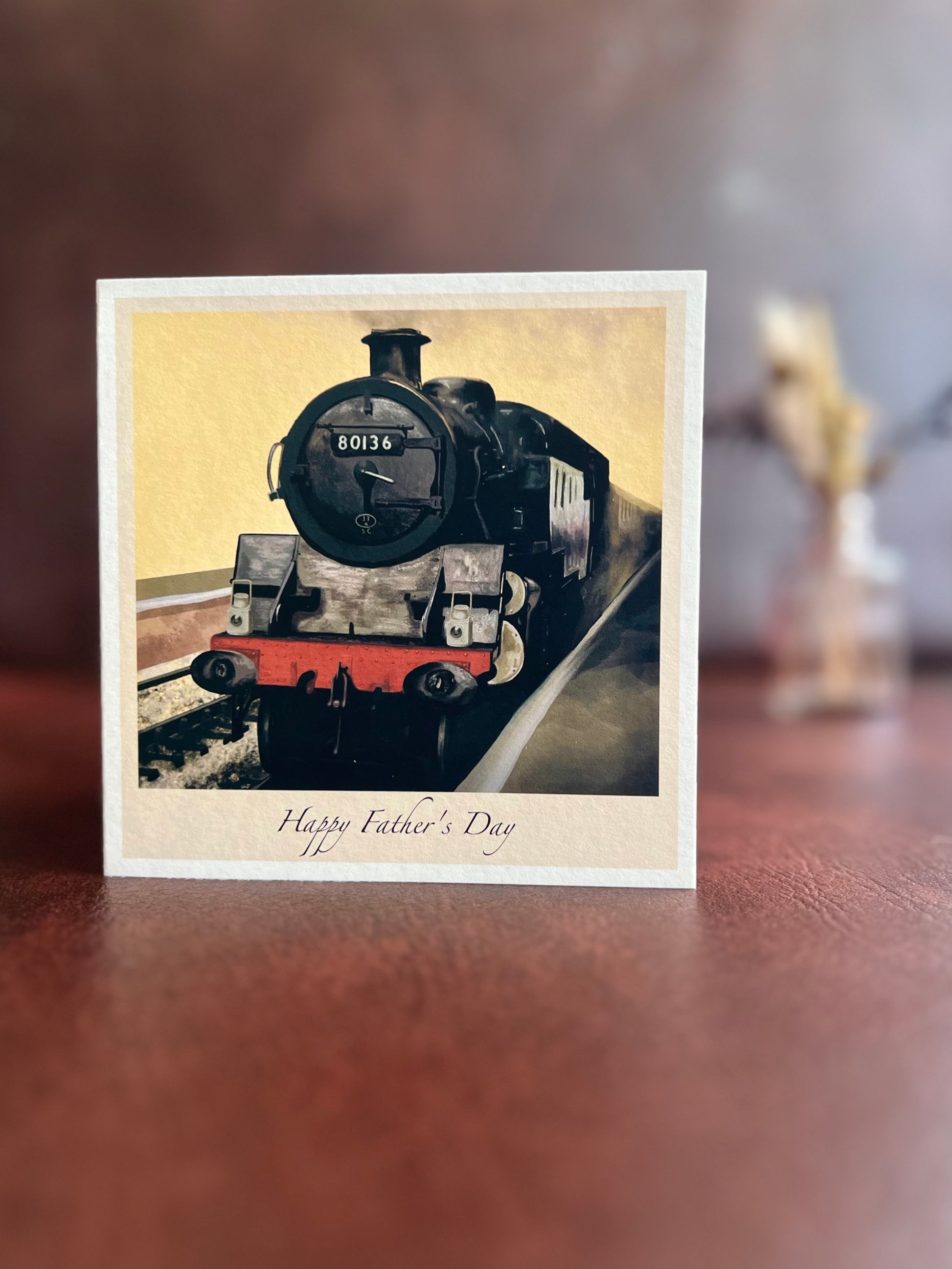 Customisable Father’s Day card featuring steam locomotive 80136 from the North Yorkshire Moors Railway, displayed on a brown leatherette tabletop with dried flowers softly blurred in the background.