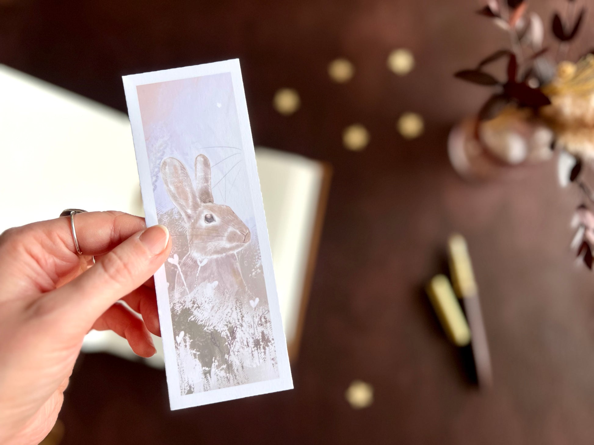 Rabbit bookmark shown with a fountain pen and open sketchbook on a cosy writing desk with soft pastel floral inspired styling.