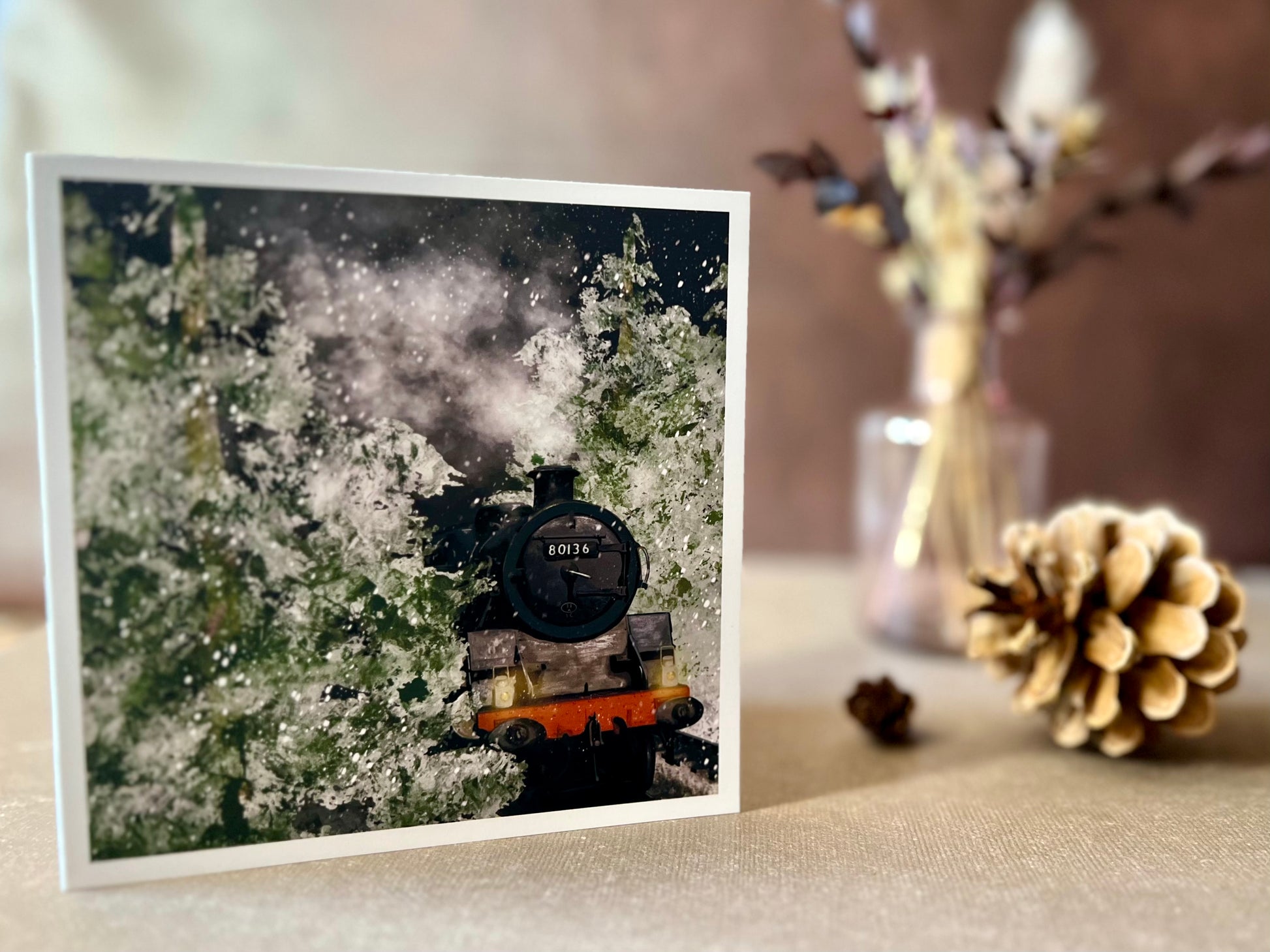 Premium illustrated Christmas greeting card featuring steam engine 80136 travelling through a snow-covered forest at night with frosted trees and steam rising into the night sky, displayed standing upright on a tabletop. Festive railway-themed winter scene card for train enthusiasts.