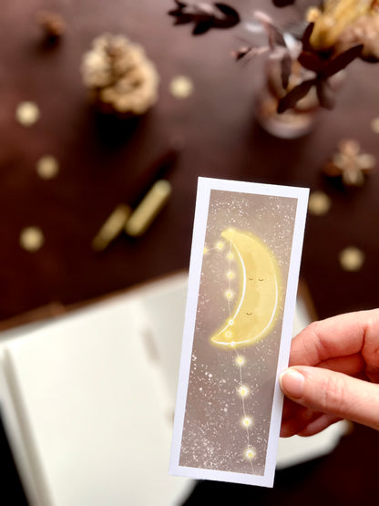 A beautiful, peaceful illustration of a smiling moon adorned with fairy lights, set against a light brown starry night sky. A lovely addition to a nighttime reading routine. 