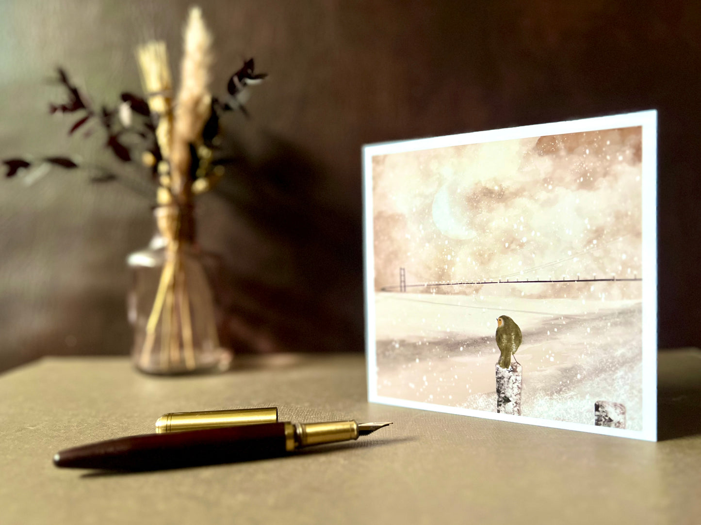 Greeting card featuring a robin and Humber Bridge winter scene, shown with a recycled kraft envelope. The card is blank inside for writing messages.