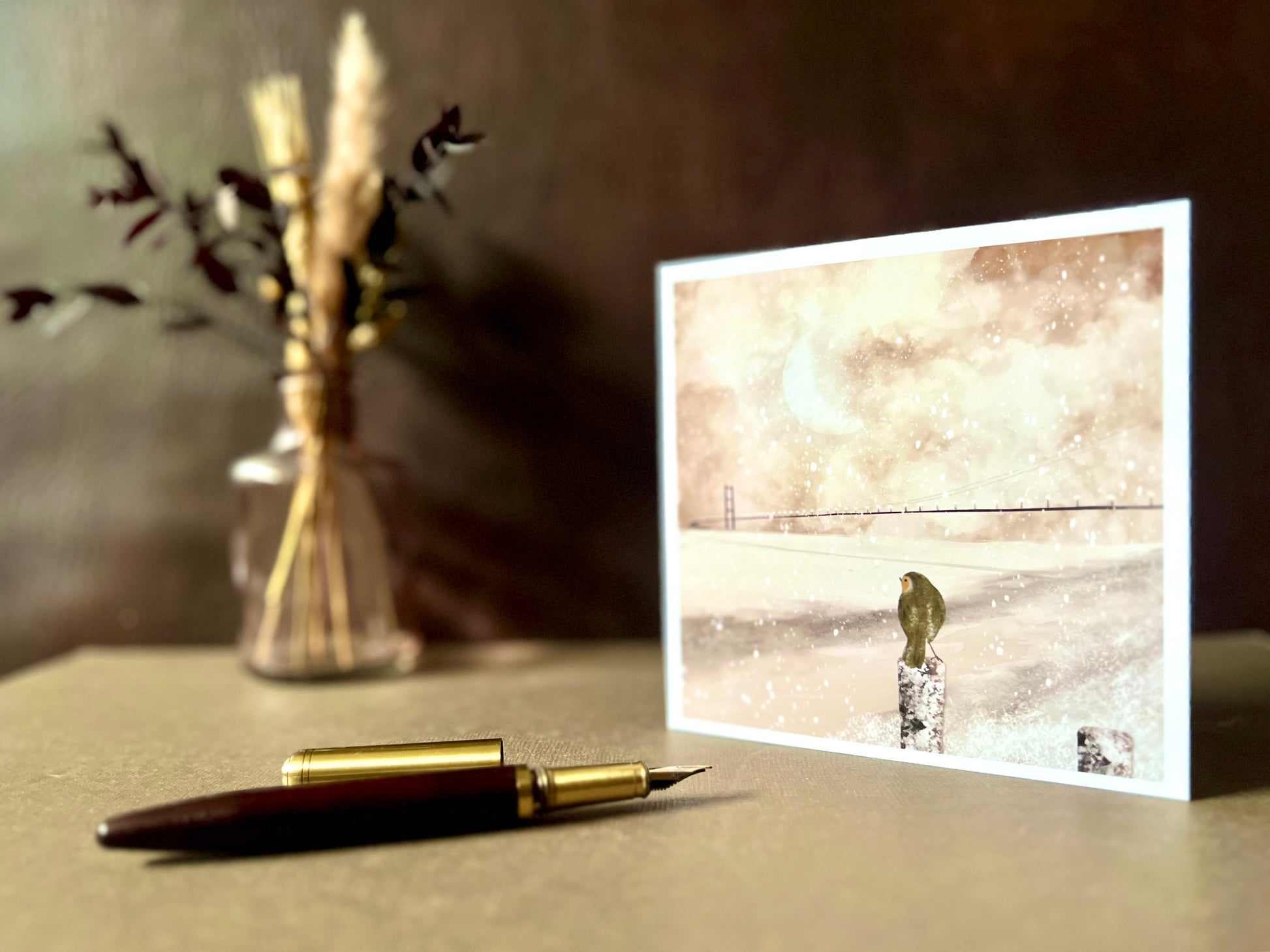 Greeting card featuring a robin and Humber Bridge winter scene, shown with a recycled kraft envelope. The card is blank inside for writing messages.