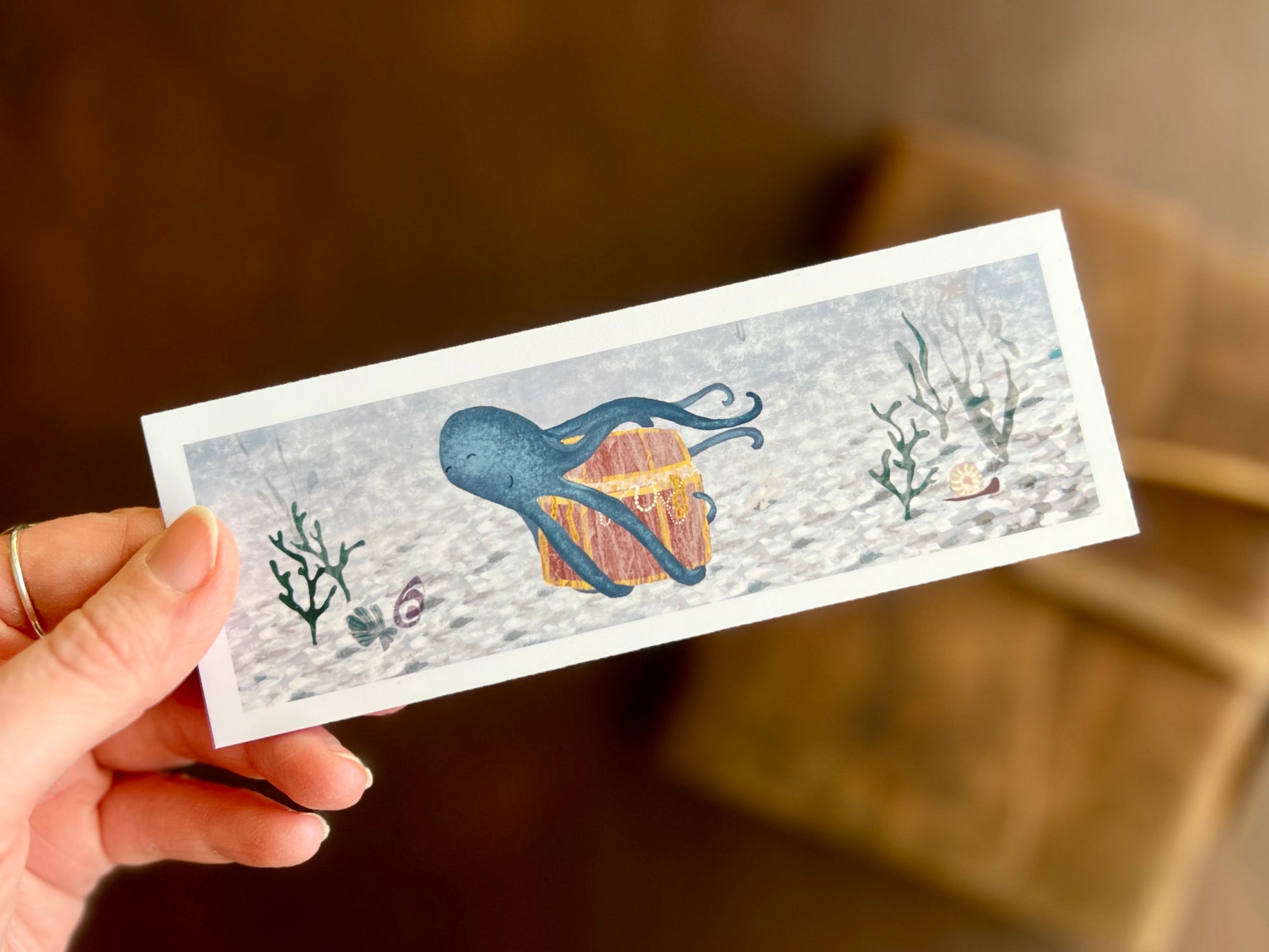 Ocean themed bookmark with a blue octopus and treasure illustration by UK artist. 
