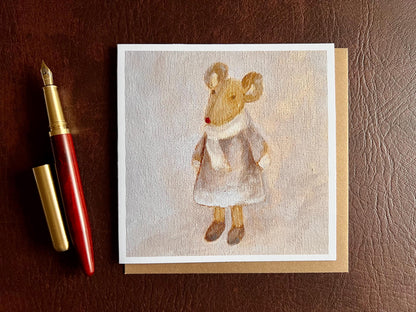 Flat lay image of an artisan greeting card featuring a print of an oil painting titled 'Mouse in Lilac Dress', shown laid flat on a tabletop with its kraft envelope and a fountain pen in a styled composition.