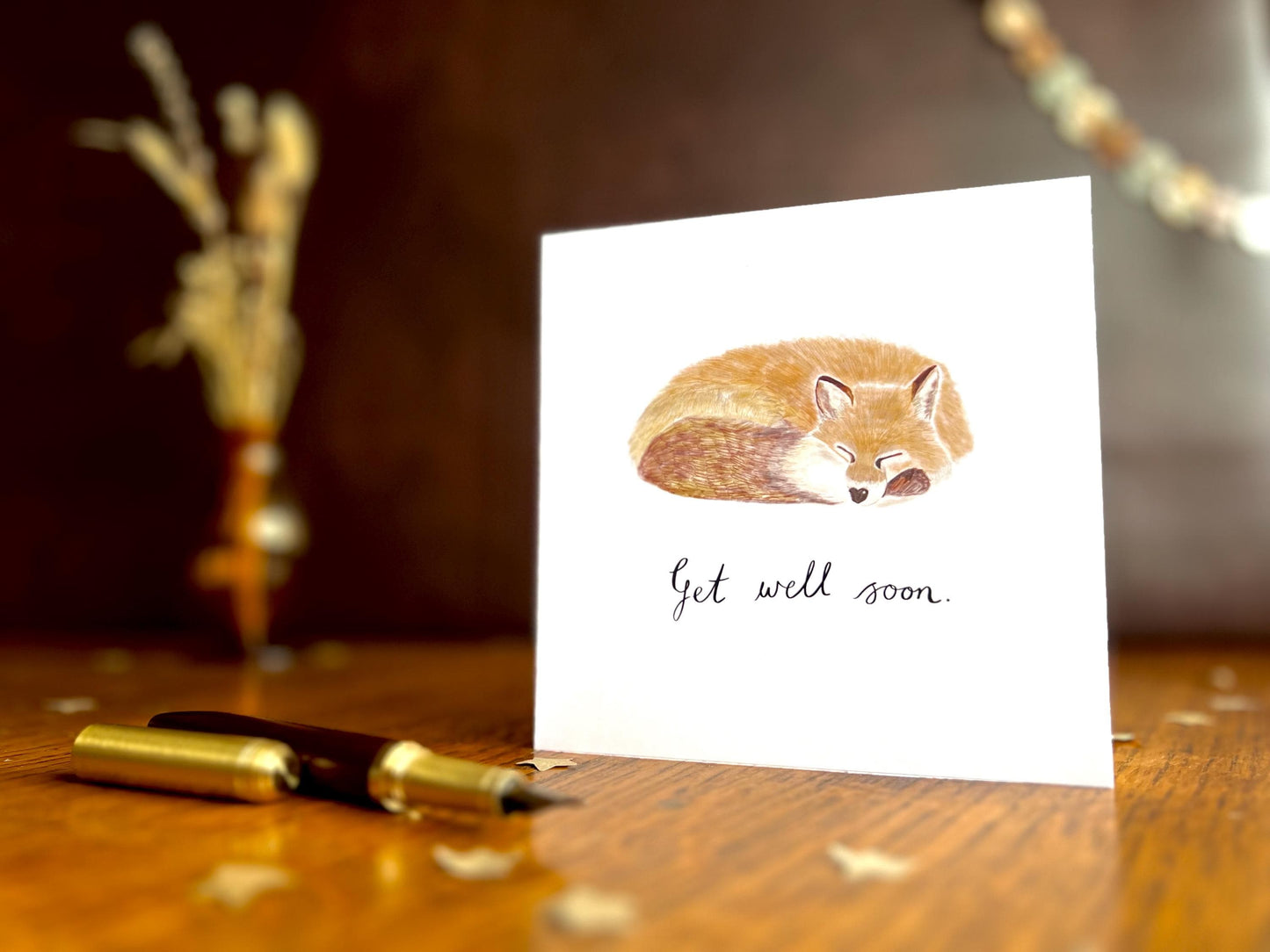 Artisan get well soon card featuring an illustration of a sleeping fox on a plain white background, shown standing upright on a tabletop in a simple lifestyle display.