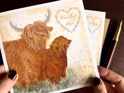 Hands holding an artisan greeting card being removed from a kraft envelope, featuring an illustration of two Highland cows on a lemon yellow background. A floral heart border in the top corner allows space for custom text such as a name, age or special date for occasions like birthdays, Mother’s Day or anniversaries.