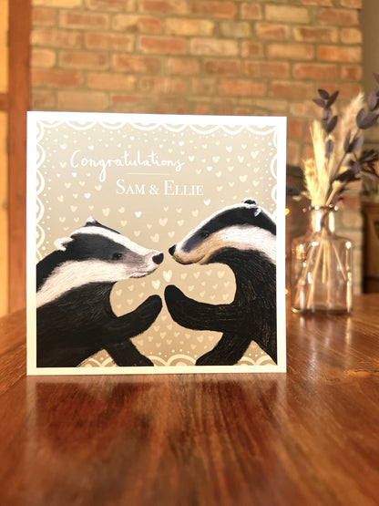 Greeting card with two badgers facing each other on a wooden surface with a brick wall background. Artist made card with design for all couples