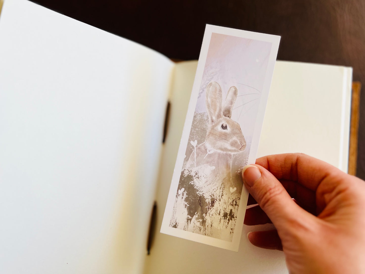 Artisan bookmark being placed in an open sketchbook. 