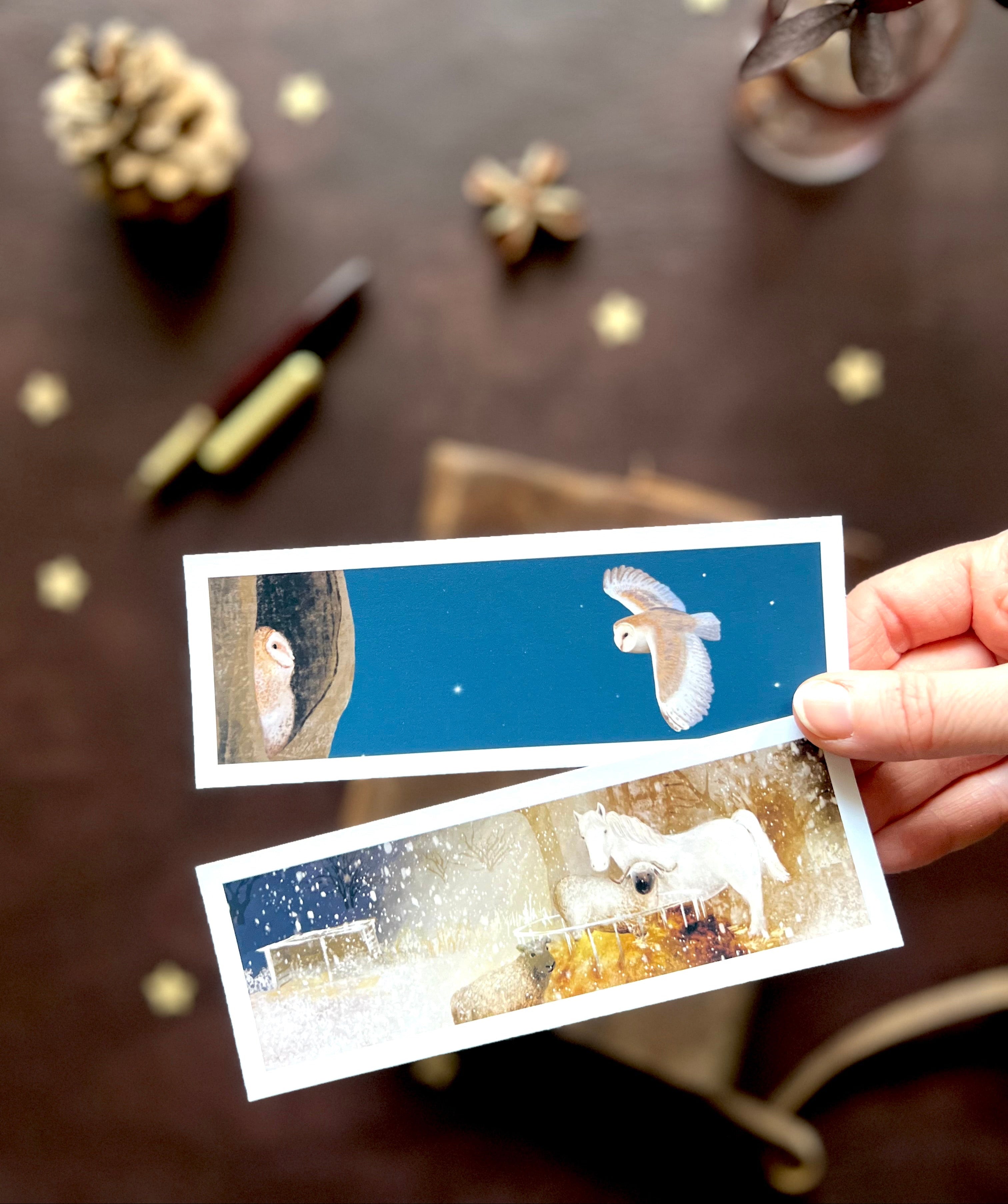 Close-up of handmade wholesale bookmarks featuring original nighttime animal illustrations, including a barn owl and owlet and a snowy horse with sheep, designed and made in East Yorkshire.