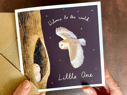 Personalised Owl New Baby Greeting Card showing the front illustration of a barn owl flying to its baby in a woodland night scene, with handwritten text “Welcome to the World, Little One” and a rich dark purple background (Standard Card). Newborn baby celebration card.