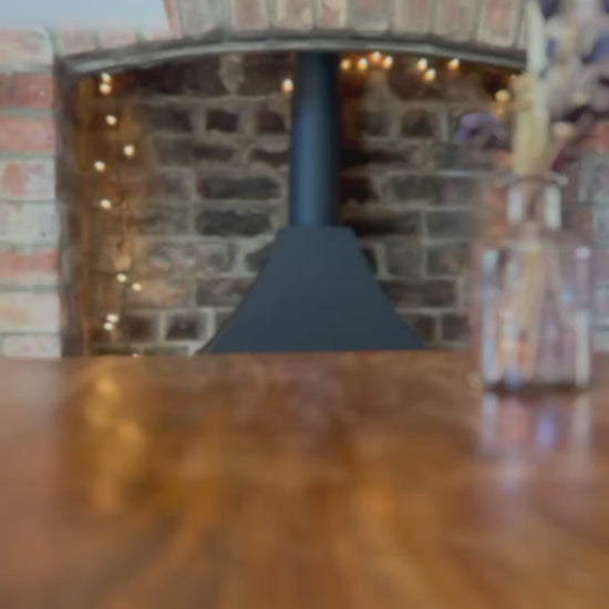 Slow pan video showing a range of personalised engagement card designs placed one at a time on a rustic wooden table, in front of a farmhouse-style brick fireplace with warm fairy lights in the background, featuring illustrated badger designs and gender-neutral congratulations cards suitable for Mr & Mr, Mrs & Mrs or Mr & Mrs couples, including son and daughter in law gifting options